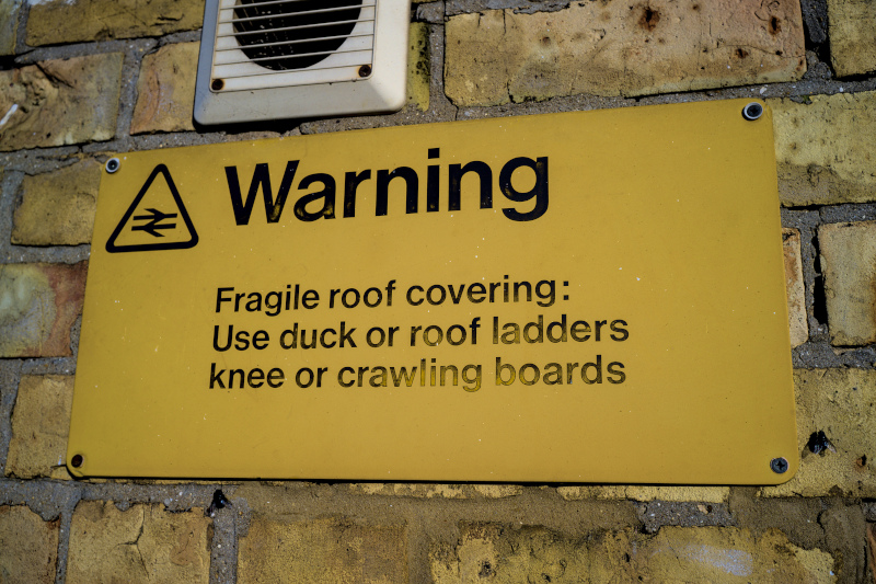 A yellow British Rail sign warning of a fragile roof covering.